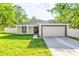 Charming single-story home with a well-maintained lawn, white fence, and a two-car garage at 13314 Se 41St Ct, Belleview, FL 34420