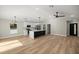 Open-concept living space with a sleek kitchen island, stainless appliances, and wood-look flooring at 13314 Se 41St Ct, Belleview, FL 34420
