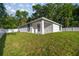 Rear exterior showcasing the lush green lawn, covered porch, and privacy provided by a white fence at 13314 Se 41St Ct, Belleview, FL 34420