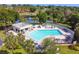 Aerial view showcasing community pool with lounge chairs, tables, umbrellas, and lush landscaping at 15917 Hidden Lake Cir, Clermont, FL 34711