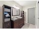 Bathroom with double sink vanity, dark wood cabinets, and a storage shelving unit at 15917 Hidden Lake Cir, Clermont, FL 34711