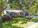 Single story home surrounded by lush landscaping, a green lawn, and mature shade trees at 15917 Hidden Lake Cir, Clermont, FL 34711