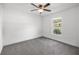 A spacious bedroom features neutral gray carpeting, a ceiling fan, and a window view of the street at 16062 Se 89Th Ter, Summerfield, FL 34491