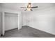 A light-filled bedroom boasts neutral gray carpeting, a ceiling fan, and a closet with bi-fold doors at 16062 Se 89Th Ter, Summerfield, FL 34491