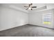 A spacious bedroom features neutral gray carpeting, a tray ceiling with fan, and a sunlit window at 16062 Se 89Th Ter, Summerfield, FL 34491
