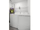 This is a well-lit laundry room featuring a standard washer, dryer and overhead wire shelving at 16062 Se 89Th Ter, Summerfield, FL 34491