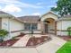 Inviting front entrance with a decorative walkway, lush landscaping, and covered porch with attractive columns at 17233 Se 115Th Terrace Rd, Summerfield, FL 34491