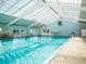 The indoor pool area features a vaulted ceiling, large windows, and ample space for swimming and recreation at 17233 Se 115Th Terrace Rd, Summerfield, FL 34491