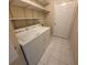 Functional laundry area with washer, dryer, shelving, and a tile floor at 17522 Se 96Th Ct, Summerfield, FL 34491