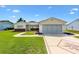 Charming single-story home featuring a manicured lawn, decorative driveway, and attached garage at 17576 Se 96Th Ct, Summerfield, FL 34491