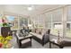 Sunroom with cozy wicker seating, screened windows and ceiling fan, offering relaxed atmosphere at 17576 Se 96Th Ct, Summerfield, FL 34491