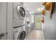 Stacked laundry machines and storage in the tiled laundry room with backyard access at 1852 Ne 39Th Ct, Ocala, FL 34470