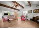 Comfortable living room featuring wood beams, modern ceiling fan, and access to outdoor space at 1852 Ne 39Th Ct, Ocala, FL 34470