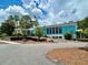 Striking blue building features a covered drive, lush landscaping, and an American flag under a partly cloudy sky at 20861 Sw 81St Loop, Dunnellon, FL 34431