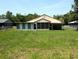 Home's backyard features ample grassy space and a covered patio area at 21298 Sw Peach Blossom St, Dunnellon, FL 34431