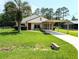 Charming single-story home with a well-maintained lawn, carport, and inviting front entrance at 21298 Sw Peach Blossom St, Dunnellon, FL 34431