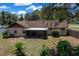Back view featuring a screened-in lanai, landscaping, and mature trees, offering a peaceful outdoor space at 23 Larch Crse, Ocala, FL 34480