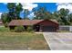 Charming single-story home featuring a well-maintained lawn, stone accents, a two-car garage, and mature trees at 23 Larch Crse, Ocala, FL 34480
