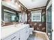 Bathroom featuring white vanity with gold hardware, decorative wallpaper, and glass-enclosed shower at 2478 Nw 53Rd Avenue Rd, Ocala, FL 34482
