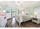 Bright main bedroom features tray ceiling, wood floors, access to outdoor patio, and floral bedding at 2478 Nw 53Rd Avenue Rd, Ocala, FL 34482