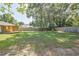 Spacious backyard with a large grassy area, wooden fence and a covered patio, ideal for outdoor activities and relaxation at 3065 Se 142Nd Ln, Summerfield, FL 34491