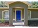 Inviting front entrance with a bright blue door framed by columns and arched entryway, flanked by matching windows at 3065 Se 142Nd Ln, Summerfield, FL 34491