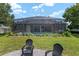 Lush backyard featuring a screened-in pool, seating area, and manicured lawn, offering a perfect blend of relaxation and entertainment at 3612 Se 47Th Ter, Ocala, FL 34480