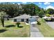 Aerial view of a charming single-story home with a stone facade, lush greenery, and a private driveway at 5060 Ne 4Th St, Ocala, FL 34470