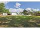 Spacious backyard with grass, a shed, a camper, and various trees under a partly cloudy sky at 5060 Ne 4Th St, Ocala, FL 34470