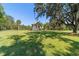 Rear exterior view of a home set amidst a large, grassy field with mature trees at 6381 Sw 21St Court Rd, Ocala, FL 34471