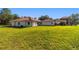 Rear view of a stylish home with a red tile roof, set on a sprawling green lawn, creating a private and serene setting at 6381 Sw 21St Court Rd, Ocala, FL 34471