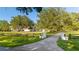 Home entrance with a long driveway, gated entry, lush lawn, and mature landscaping at 6381 Sw 21St Court Rd, Ocala, FL 34471