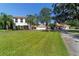 Elegant two-story home with a red tile roof, beautifully manicured lawn, and a circular driveway lined with palm trees at 6381 Sw 21St Court Rd, Ocala, FL 34471