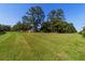Lush green yard surrounding a home with a red tile roof, bordered by mature trees and a classic wooden fence at 6381 Sw 21St Court Rd, Ocala, FL 34471