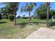 The backyard features a well-maintained lawn and palm trees, framed by a chain-link fence at 6472 Sw 106Th Pl, Ocala, FL 34476