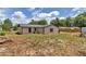 Backyard of a white house showing grass, a privacy fence, and a woodpile at 6820 Se 108Th St, Belleview, FL 34420