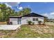 Exterior of a home with neutral siding, landscaping, trash bins, and a concrete pad at 6820 Se 108Th St, Belleview, FL 34420