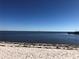 Coastal property featuring a serene beach, gentle waves, and a distant sailboat under a clear blue sky at 7134 Sw 129Th Terrace Road, Ocala, FL 34481