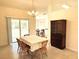 Dining room with table set for a meal, featuring elegant lighting and backyard views through sliding glass doors at 7134 Sw 129Th Terrace Road, Ocala, FL 34481