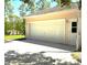 Detached garage offers parking and storage space with a sunny driveway and exterior door at 7134 Sw 129Th Terrace Road, Ocala, FL 34481