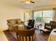 Comfortable living room featuring a plush sofa, rocking chair, and natural light streaming in through a large window at 7134 Sw 129Th Terrace Road, Ocala, FL 34481