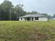 Rear exterior showing a large yard, neutral colored siding, and gray shingles at 74 Pine Trace Crse, Ocala, FL 34472