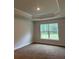 Bedroom featuring plush carpeting, tray ceiling, and a large window offering natural light and backyard views at 74 Pine Trace Crse, Ocala, FL 34472