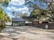 Charming home showcases its metal roof and gravel driveway near a serene lake, enveloped by lush trees and greenery at 754 Se 167Th Court Rd, Silver Springs, FL 34488