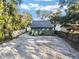 A cozy home features a metal roof and a gravel driveway next to a tranquil lake, creating a serene setting at 754 Se 167Th Court Rd, Silver Springs, FL 34488