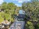 Bird's-eye view of a cozy home with a metal roof, a gravel driveway, and mature trees near a tranquil lake at 754 Se 167Th Court Rd, Silver Springs, FL 34488