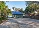 Exterior view of a charming home with a metal roof, gravel driveway, and mature trees at 754 Se 167Th Court Rd, Silver Springs, FL 34488
