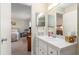 Bathroom sink and mirror, with a view into the bedroom featuring a king bed and desk at 8524 Sw 90Th Ln # B, Ocala, FL 34481