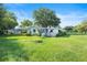 Well-maintained backyard with lush green grass, mature trees, and a white single-story home with a screen enclosure at 8973 Sw 103Rd Ln, Ocala, FL 34481