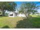 Well-maintained single-story home with white siding and a grassy yard, shaded by mature trees on a sunny day at 8973 Sw 103Rd Ln, Ocala, FL 34481